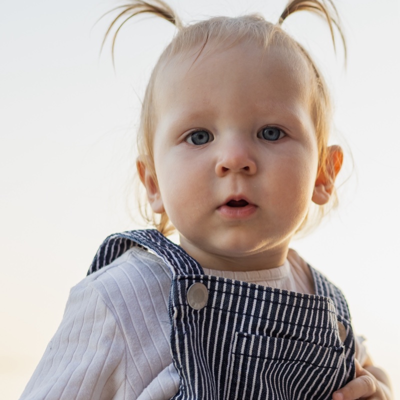 The example photo: a toddler with two small pigtails, facing the camera in soft light